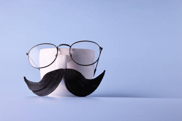 istock Man's face made of artificial mustache, glasses and cup on light blue background. Space for text 2199279230