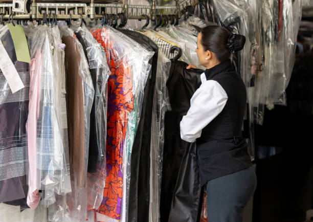 istock Employee working at the dry cleaner's hanging clothes on a rack 2199286828
