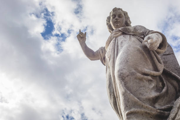 Dublin, Ireland - September 21, 2018: A weathered angel statue stands against a cloudy sky at Glasnevin Cemetery in Dublin, Ireland, symbolizing peace and remembrance.