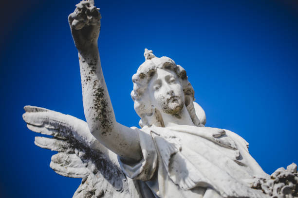 A close up of an angel statue against a deep blue morning sky,