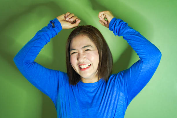 Women dancing with smiling faces on green wall