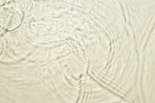 Top view background summer natural Beige surface, clear water with ripples and splashes. water waves in sunlight The water surface has waves and concept background cosmetics moisturizer toner