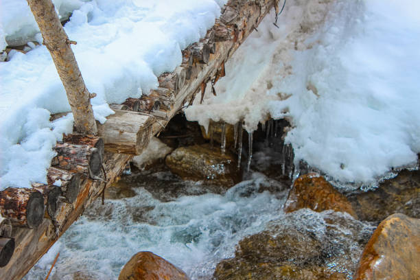 istock Scenic Winter Stream with Snow-Covered Bridge 2199293327