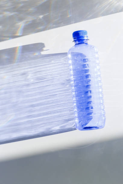 istock Clear plastic water bottles for clean water on white blue background closeup, minimal aesthetic lifestyle photo, top view, flat lay, Naural light, sunlight shadows, caustic light effect, star filter 2199301486