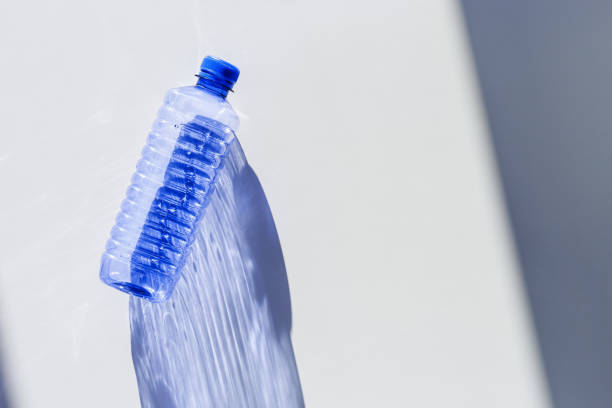 istock Clear plastic water bottles for clean water on white blue background closeup, minimal aesthetic lifestyle photo, top view, flat lay, Naural light, sunlight shadows, caustic light effect, star filter 2199301489