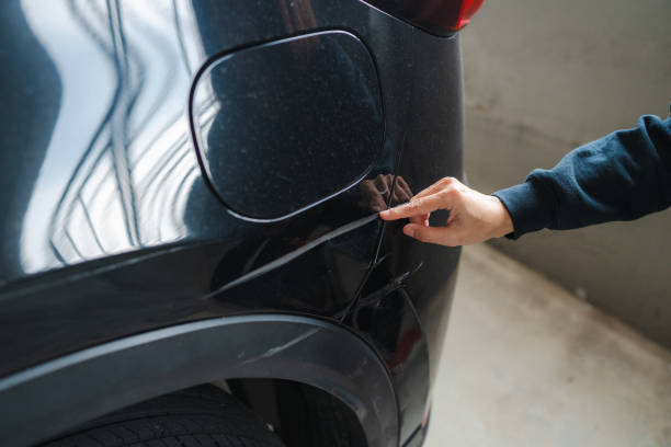 istock Woman hand pointing at dent on black car close up view 2199301540