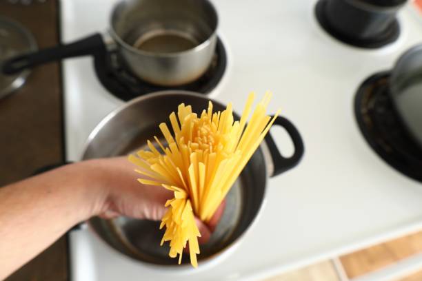 istock A hand lowers pasta into a saucepan 2199302826