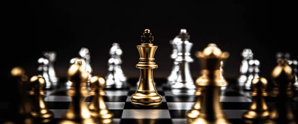 istock Close up king chess standing in the middle on chess board with silver chess concepts of business team and leadership strategy and organization management. 2199303376