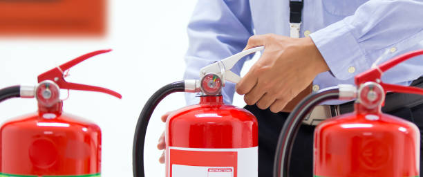 istock Firefighter checking the handle of the red fire extinguishers tank in the building concepts of prevent case for emergency and safety rescue and fire training. 2199303512