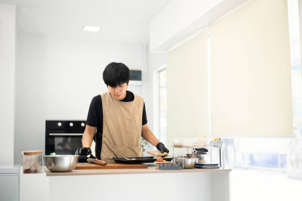 istock Handsome young asian man arranging cookie dough on a baking tray 2199307635