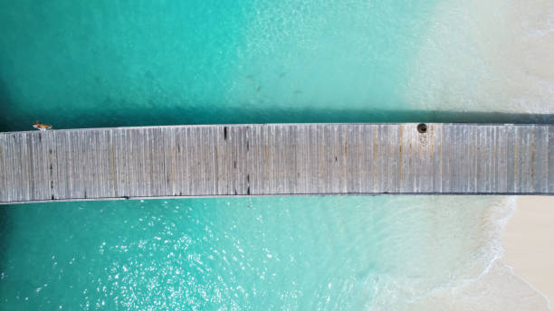 istock Wooden pier dividing turquoise water and white sand beach 2199309405
