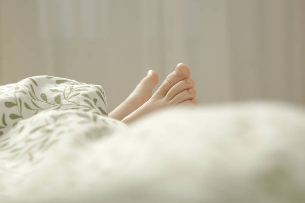 Child feet under the green and white duvet
