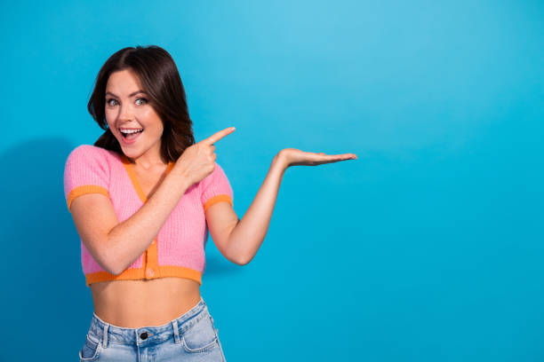 istock Cheerful young woman pointing at empty space on a blue background 2199316190
