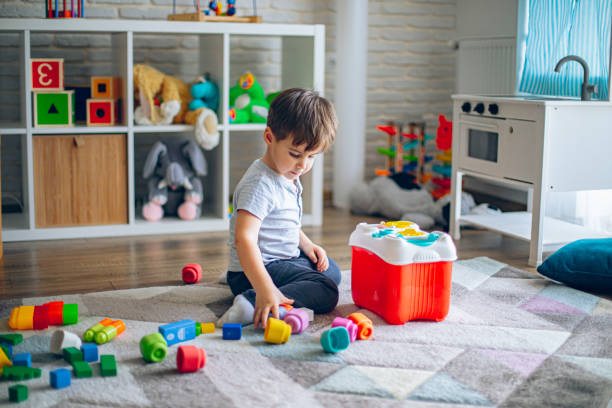 istock Little Boy Picking Up Toys after Playing at Home 2199317360