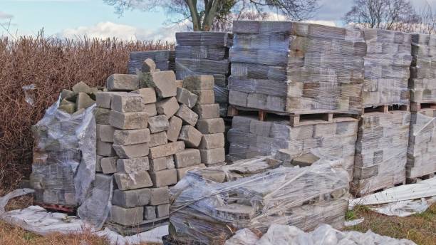 istock Stacked Concrete Cement Construction Bricks on Transport Palletes Secured with Plastic Foil Wrap Stored Outdoors 2199317560