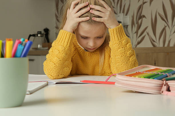 istock Exhausted elementary school girl is tired of doing homework, stressed with difficult task, sitting at the kitchen table. Home education, homeschooling concept. 2199319155