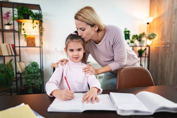 istock Mother kissing daughter while doing homework at home 2199319505