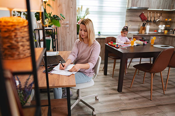 Mother working from home while her daughter is playing and drawing