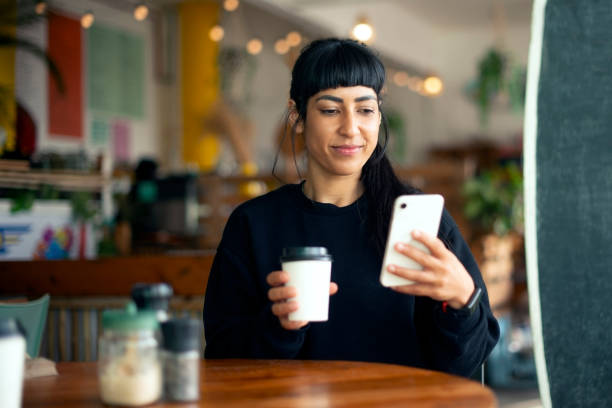 istock Coffee shop, phone and woman relax, reading notification and typing text on internet. Cafe, drink and female person on mobile for communication, online chat or scroll to download social media app 2199320587