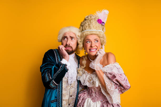 istock Elegant duo in medieval costumes posing against yellow backdrop with expressive gestures and historic charm 2199323123