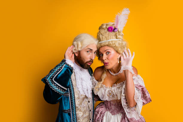 istock Noble Couple in Classical Costumes Striking a Whimsical Pose Against a Vibrant Yellow Background Highlighting Historical Elegance 2199323135