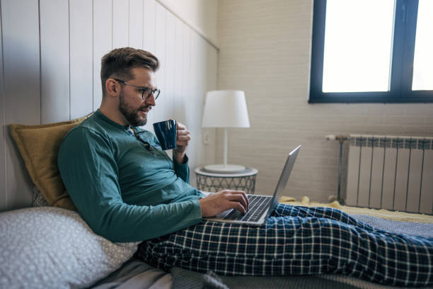 istock Mid adult man working remotely from bed 2199323165