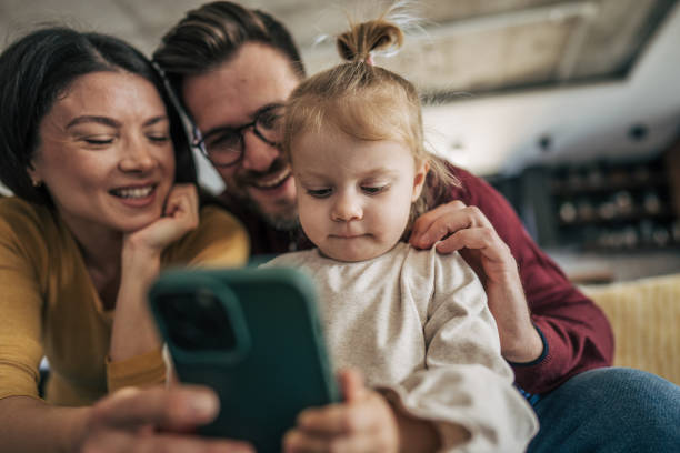 istock Happy family watching smartphone at home 2199323894