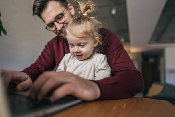 istock Father working from home with his baby daughter on his lap 2199325153