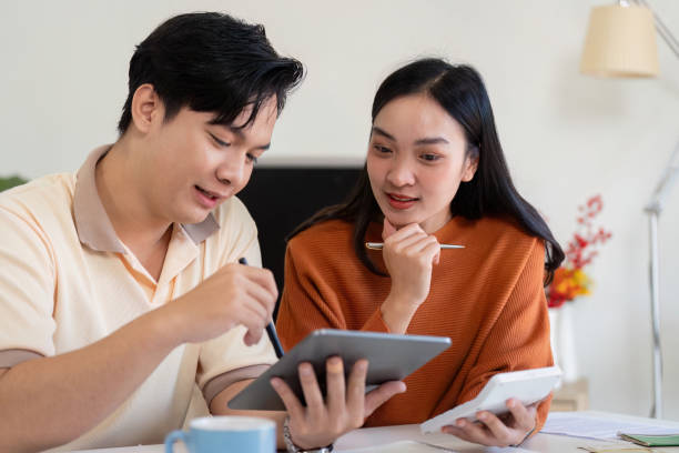 istock Couple discussing finances while reviewing bills and using a tablet, fostering collaboration in budgeting. 2199325602