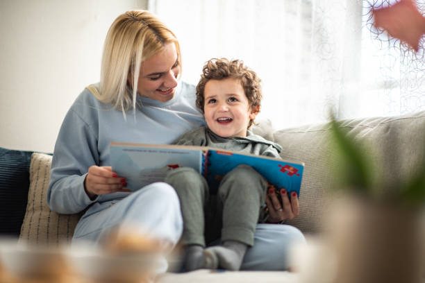 Young mother reading a story to her toddler in living room.