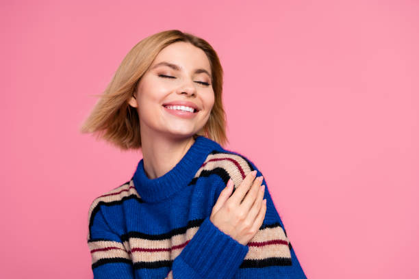 istock Charming Young Woman in Blue Sweater Smiling Joyfully Against a Pink Background 2199327392