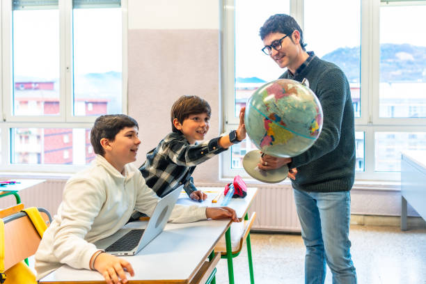 istock Teacher holding globe, engaging with students in geography lesson 2199327894