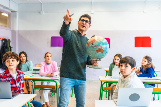 insegnante di geografia che tiene il globo e punta alla mappa in classe - paese area geografica foto e immagini stock