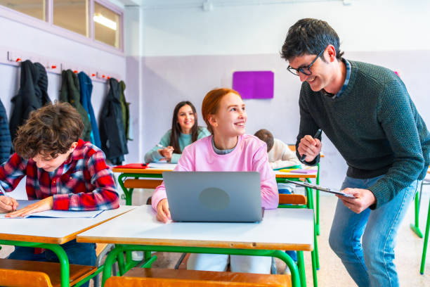 istock Teacher helping a teenage student using a laptop in the classroom 2199327967