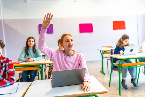 istock Teenage student raising hand in classroom with laptop 2199328073