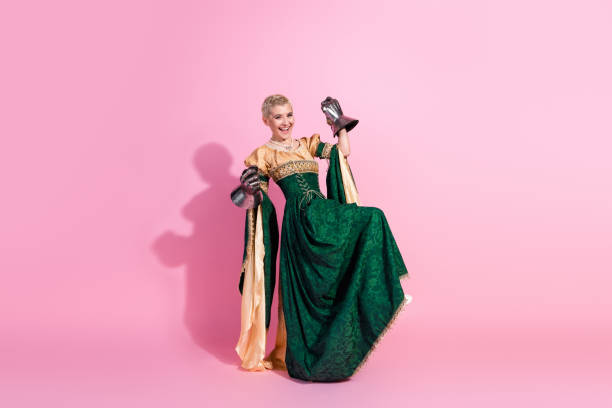 istock Young woman in elegant medieval costume posing with a playful expression on a pink background 2199328083