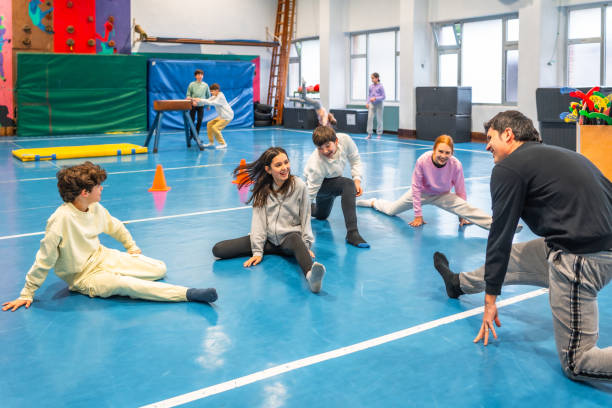 istock Students stretching with their teacher in the school gym 2199328294