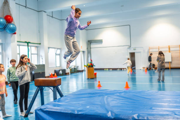 istock Elementary age girl jumping over vaulting box in gym class 2199328307