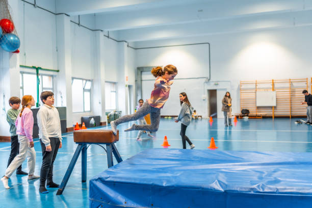 istock Elementary age girl jumping over pommel horse during physical education class 2199328309
