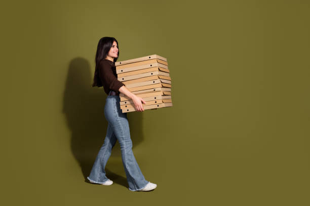 istock Stylish young woman carrying stack of boxes against khaki background 2199330064