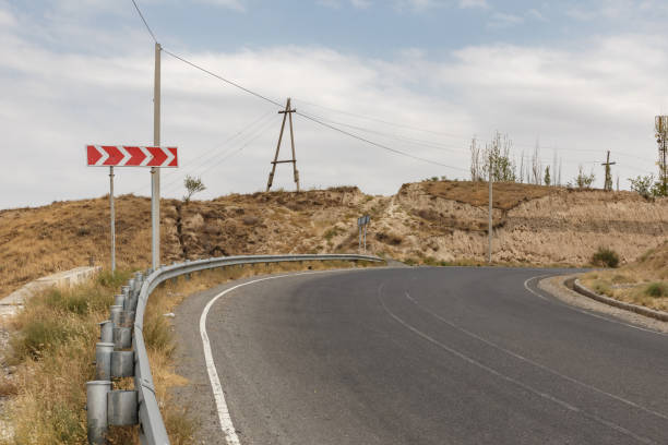 istock Winding road through arid landscape in Tajikistan during a cloudy day 2199330081