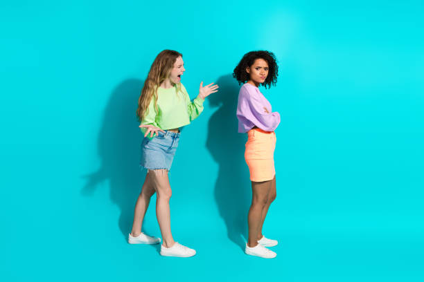 istock Two young women interacting dramatically on a vivid turquoise background, showcasing trendy casual outfits and emotional expressions 2199333195