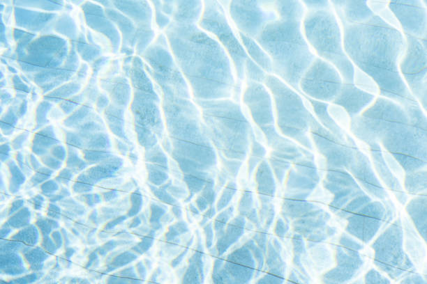 Sunlight streaming through water, casting luminous geometric patterns across swimming pool surface, evoking peaceful underwater ambiance in a summer day