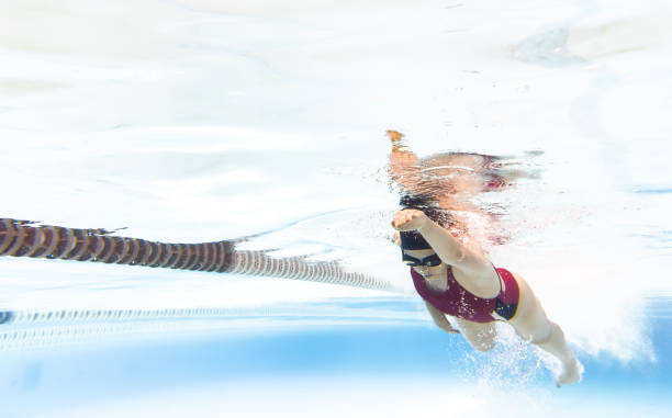 istock Female underwater swimmer in red swimsuit gliding through clear pool water, creating bubbles and reflections, symbolizing fitness, sport and aquatic movement 2199335743