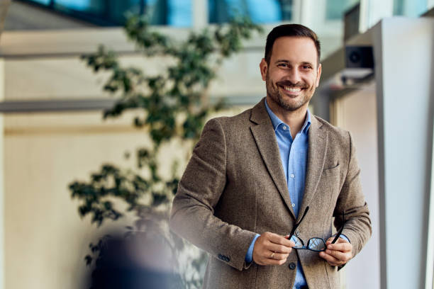 istock Confident Professional Smiling Indoors in Bright Office Environment Holding Glasses 2199340113