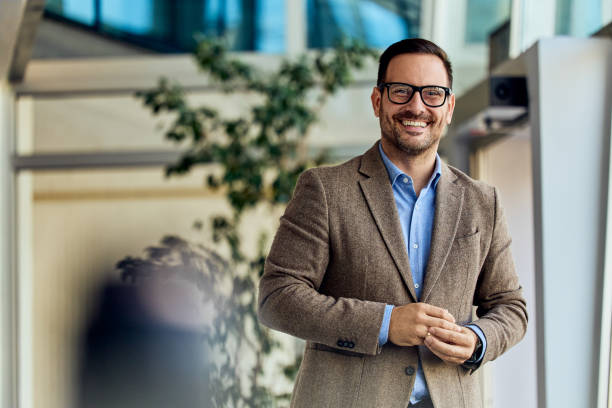 istock Confident Businessman Smiling in a Modern Office with Glass and Natural Light 2199340119
