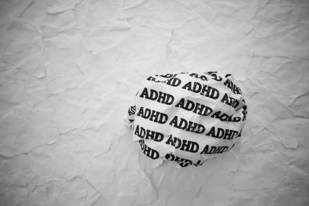 istock Crumpled paper ball with words ADHD on torn white paper pieces background. 2199340150