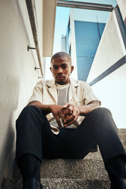 Confident Young Man Sitting on Stairs with Modern Urban Background