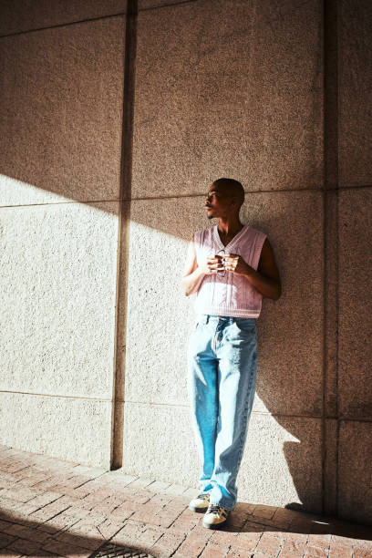 istock Young Individual Standing Against an Urban Wall Bathed in Afternoon Sunlight 2199341741