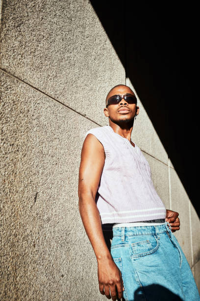 Stylish Individual Posed Against a Wall in Direct Sunlight